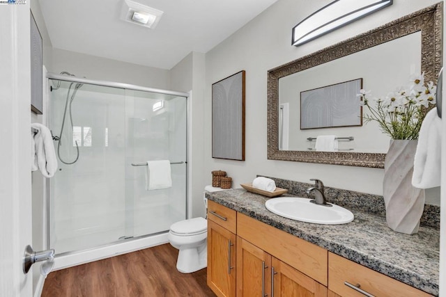 bathroom featuring walk in shower, vanity, toilet, and hardwood / wood-style floors