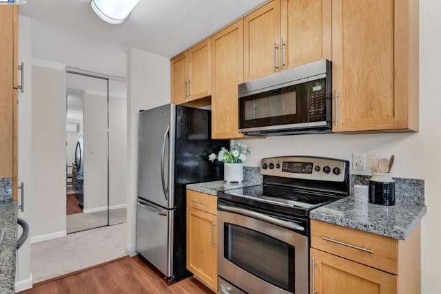 kitchen featuring light stone countertops, light brown cabinets, stainless steel appliances, and light wood-type flooring