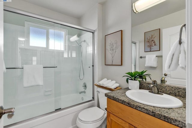 full bathroom with vanity, enclosed tub / shower combo, and toilet