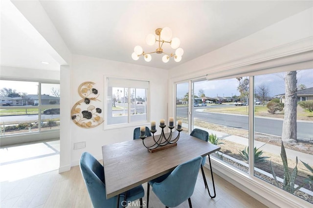 dining area featuring a healthy amount of sunlight, light wood-style floors, baseboards, and a notable chandelier