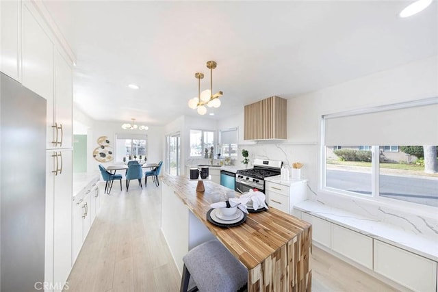 kitchen featuring white cabinets, a chandelier, stainless steel appliances, and hanging light fixtures