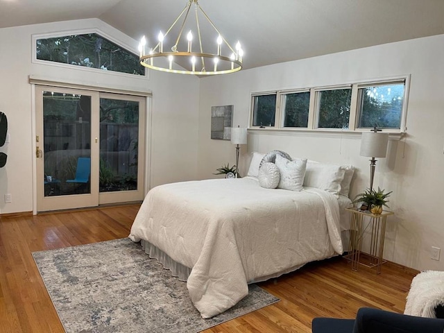 bedroom featuring hardwood / wood-style flooring, lofted ceiling, access to exterior, and a chandelier