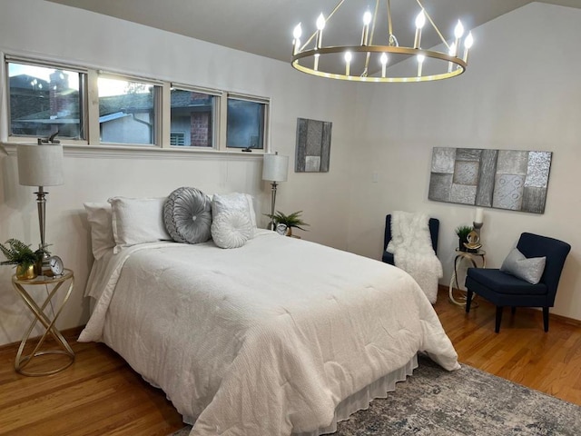 bedroom with hardwood / wood-style flooring, lofted ceiling, and a notable chandelier