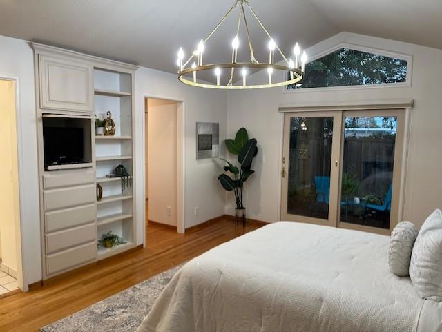 bedroom featuring an inviting chandelier, wood-type flooring, vaulted ceiling, and access to outside