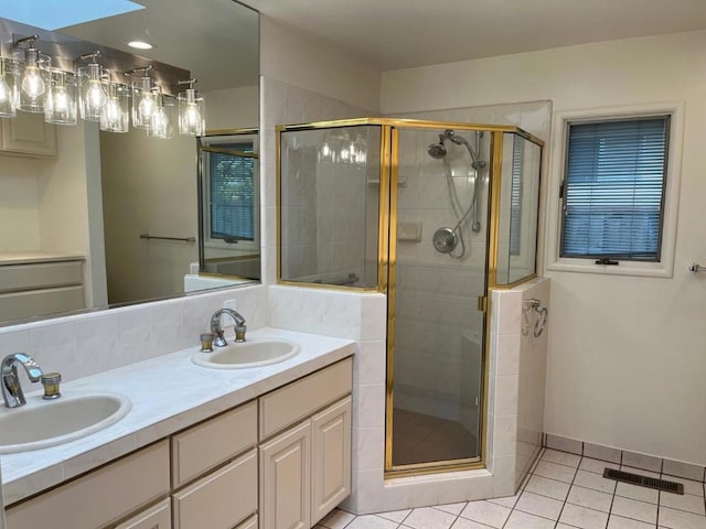 bathroom featuring tile patterned flooring, vanity, an enclosed shower, and a skylight