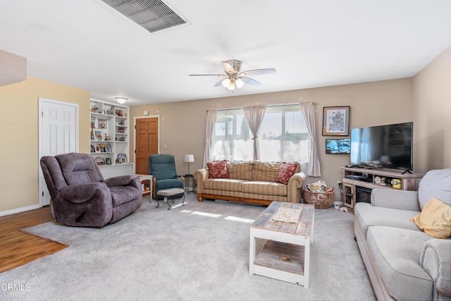 living area with visible vents, baseboards, wood finished floors, and a ceiling fan