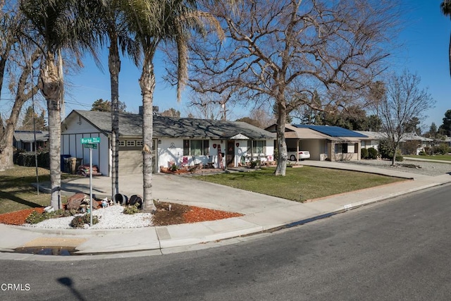 view of front of house featuring a residential view, an attached garage, concrete driveway, and a front yard