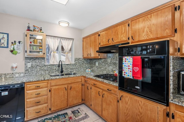 kitchen featuring tasteful backsplash, under cabinet range hood, light tile patterned floors, black appliances, and a sink