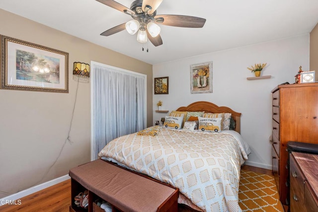 bedroom featuring ceiling fan, baseboards, and wood finished floors