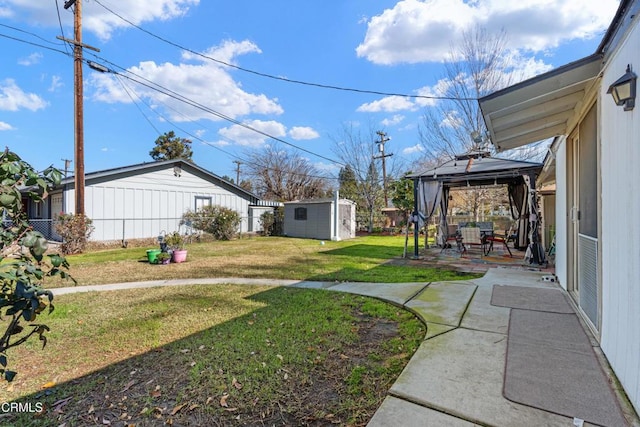 view of yard with fence, a gazebo, a shed, an outdoor structure, and a patio area