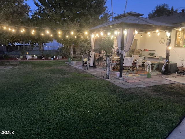 yard at twilight featuring a gazebo, a patio, and fence