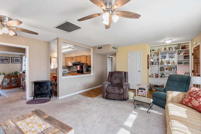 living area featuring a wood stove, visible vents, and light carpet