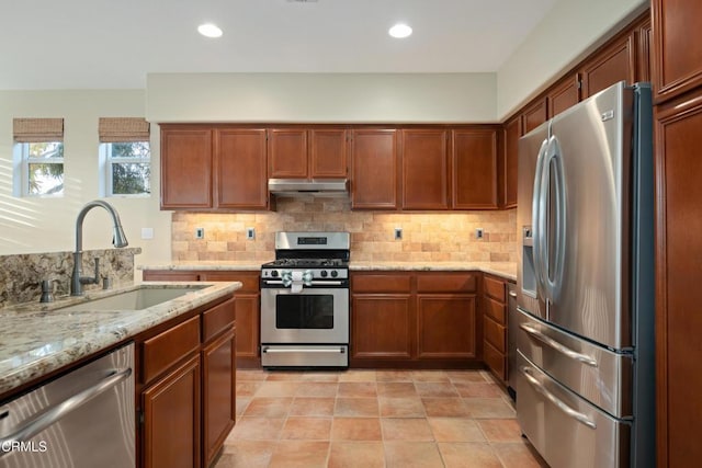 kitchen featuring tasteful backsplash, sink, light stone countertops, and appliances with stainless steel finishes