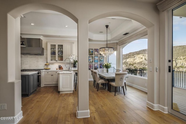 kitchen with wall chimney range hood, a mountain view, sink, and white cabinets