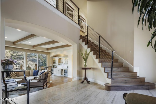 stairway with beamed ceiling and a high ceiling