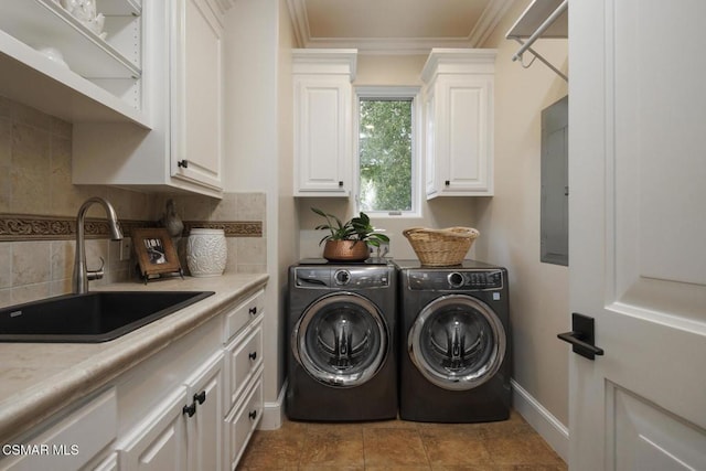 clothes washing area featuring washing machine and clothes dryer, sink, crown molding, cabinets, and electric panel