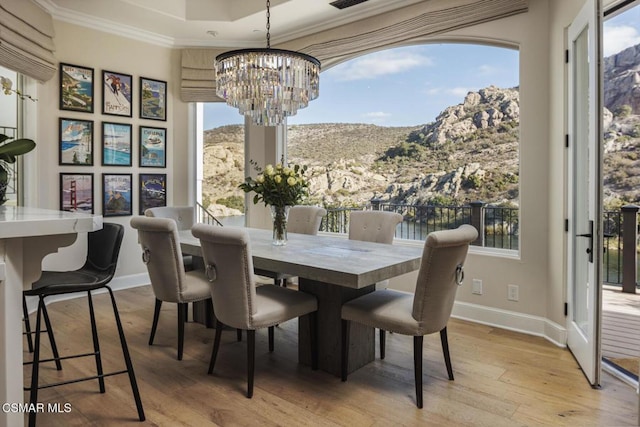 dining space featuring ornamental molding, a mountain view, a chandelier, and light hardwood / wood-style floors