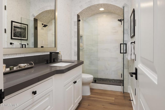 bathroom featuring vanity, wood-type flooring, a shower with shower door, and toilet