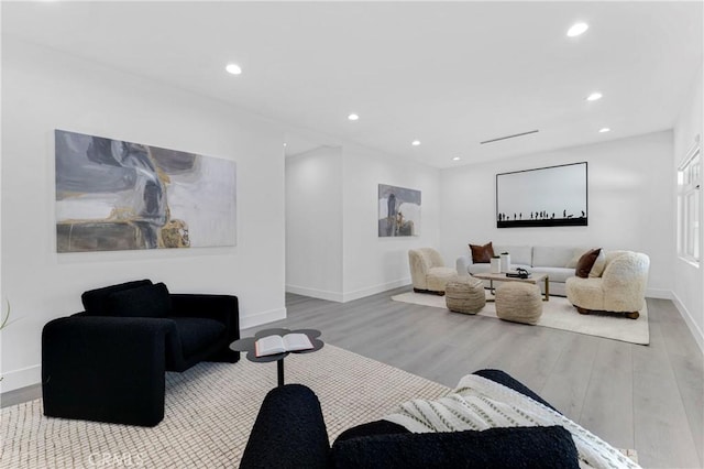 living area featuring baseboards, wood finished floors, and recessed lighting