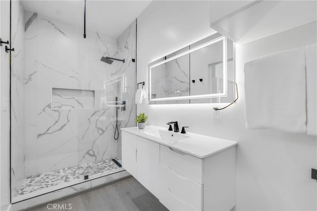 full bath featuring vanity, a marble finish shower, and wood finished floors