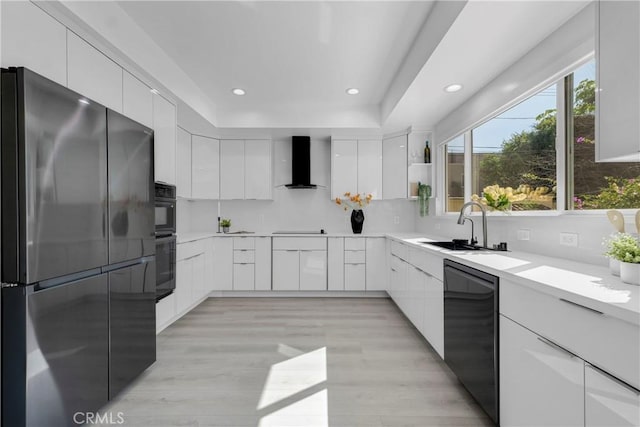 kitchen with black appliances, wall chimney range hood, modern cabinets, and a sink