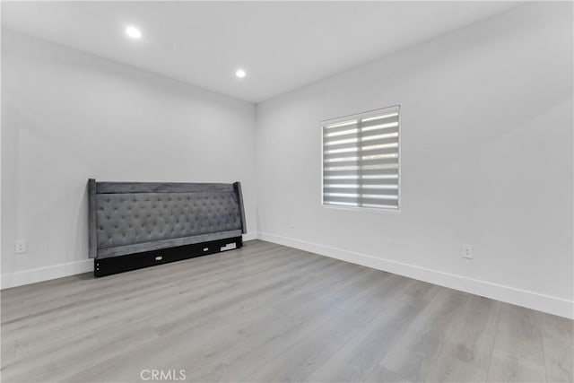 unfurnished bedroom with baseboards, wood finished floors, and recessed lighting