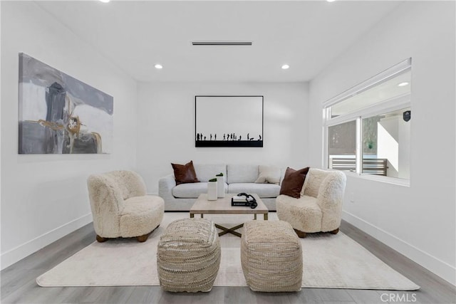 living area with recessed lighting, wood finished floors, visible vents, and baseboards