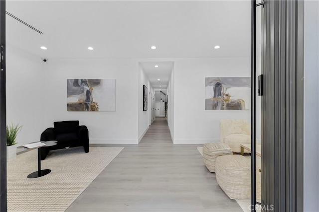 hallway featuring baseboards, wood finished floors, and recessed lighting