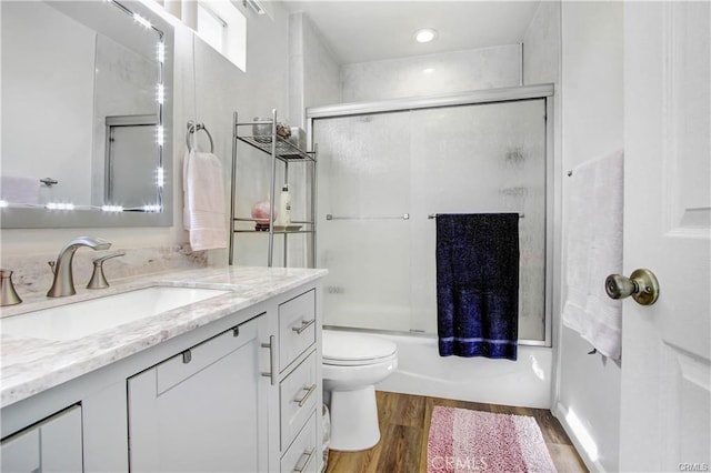 full bathroom with vanity, wood-type flooring, shower / bath combination with glass door, and toilet