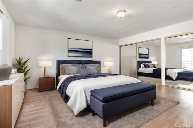 bedroom featuring two closets and light wood-type flooring