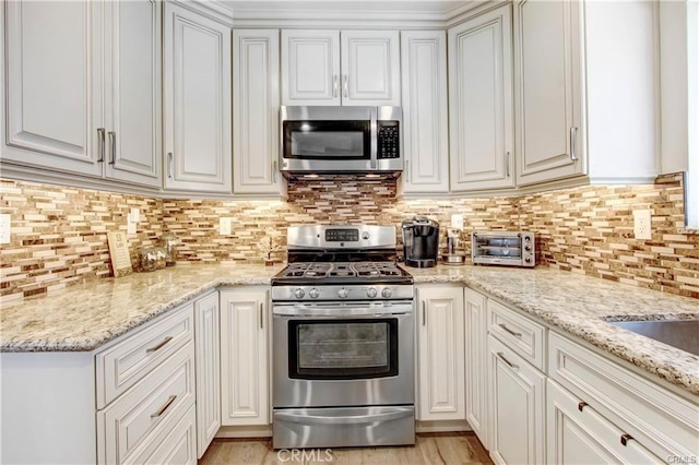 kitchen with white cabinetry, light stone counters, and stainless steel appliances