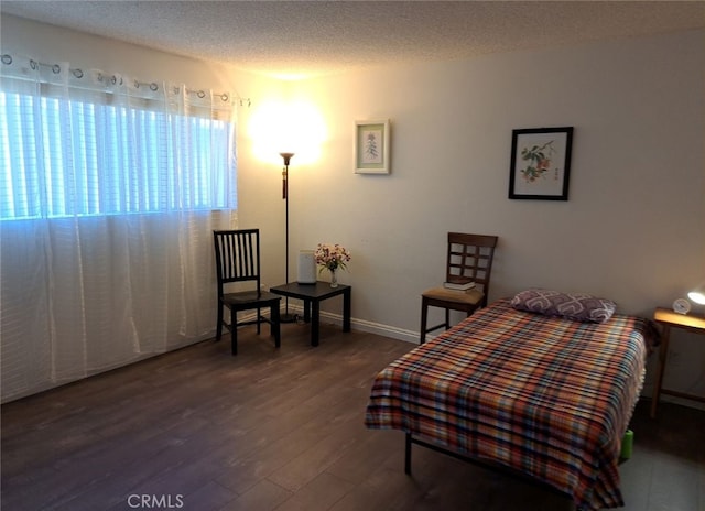 bedroom featuring a textured ceiling and dark hardwood / wood-style flooring