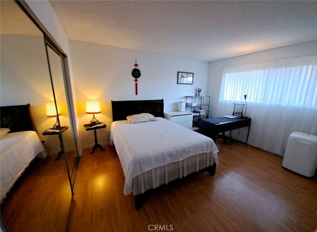 bedroom with dark wood-type flooring, a closet, and a textured ceiling