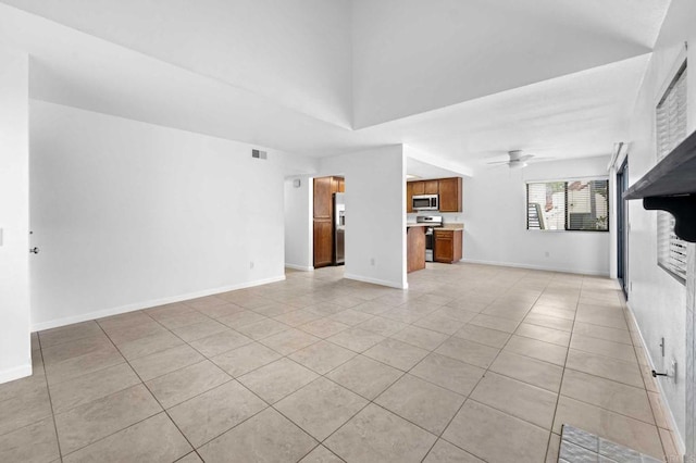 unfurnished living room with a towering ceiling, light tile patterned floors, and ceiling fan