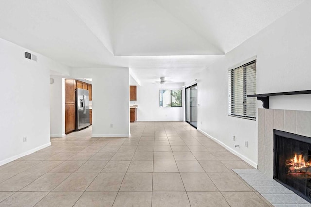 unfurnished living room featuring lofted ceiling, a fireplace, ceiling fan, and light tile patterned flooring