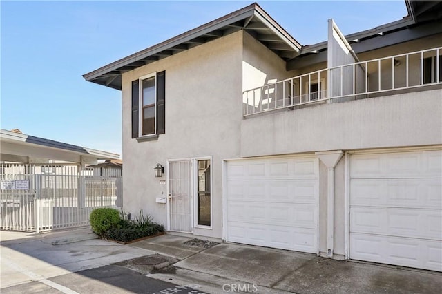 view of front facade with concrete driveway, fence, an attached garage, and stucco siding