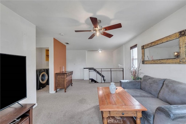 living room featuring ceiling fan, light colored carpet, and washer / dryer