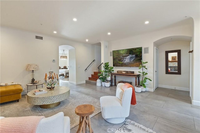 living room featuring arched walkways, recessed lighting, visible vents, baseboards, and stairs