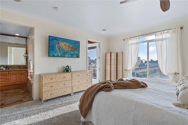 bedroom with connected bathroom, light colored carpet, a sink, a ceiling fan, and access to exterior