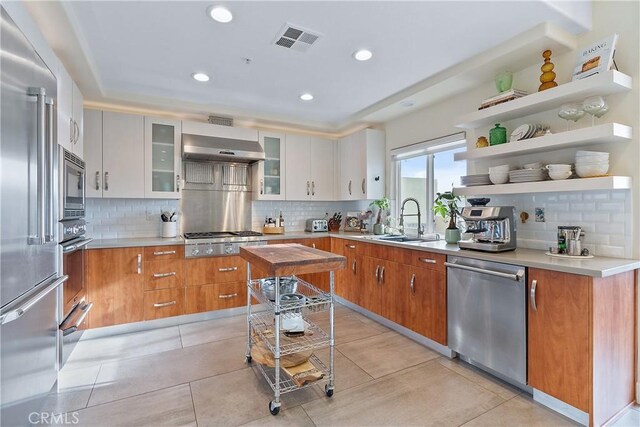 kitchen featuring appliances with stainless steel finishes, exhaust hood, white cabinets, and light tile patterned floors