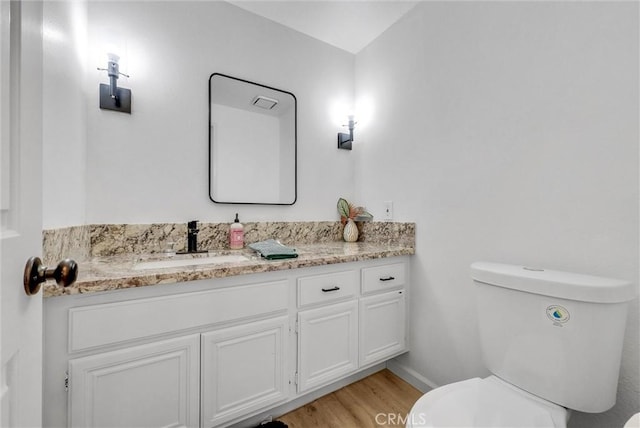 bathroom with hardwood / wood-style flooring, vanity, and toilet