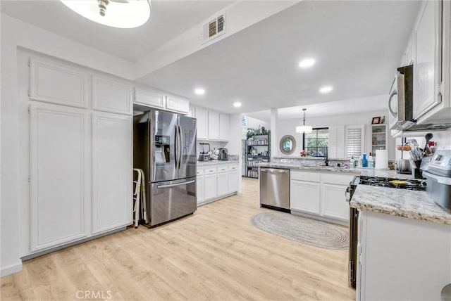 kitchen featuring white cabinetry, appliances with stainless steel finishes, light hardwood / wood-style flooring, and decorative light fixtures