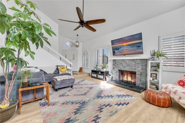 living room with wood-type flooring, vaulted ceiling, and a fireplace