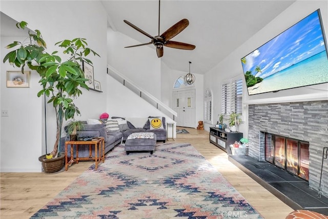 living room with wood-type flooring, high vaulted ceiling, ceiling fan, and a fireplace