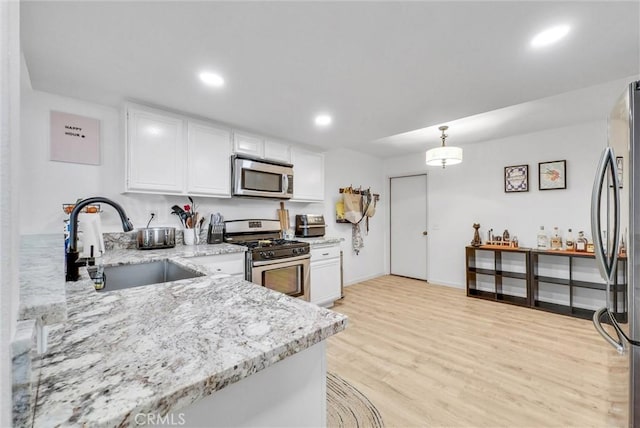 kitchen featuring hanging light fixtures, appliances with stainless steel finishes, sink, and white cabinets