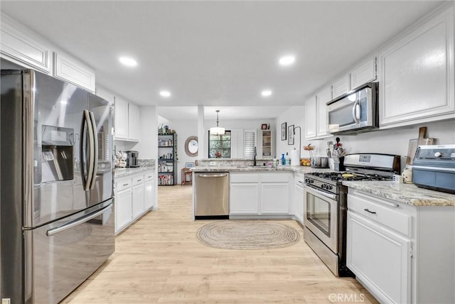 kitchen featuring pendant lighting, sink, appliances with stainless steel finishes, white cabinetry, and kitchen peninsula