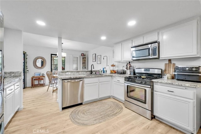 kitchen featuring stainless steel appliances, kitchen peninsula, and white cabinets