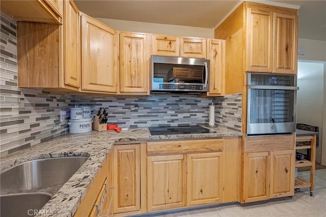 kitchen featuring stainless steel appliances, light brown cabinetry, light stone countertops, and sink