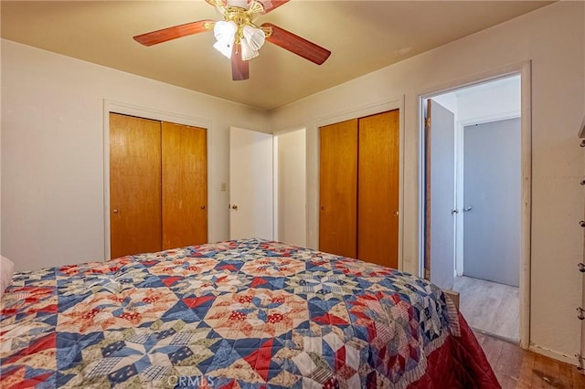 bedroom featuring hardwood / wood-style floors, multiple closets, and ceiling fan