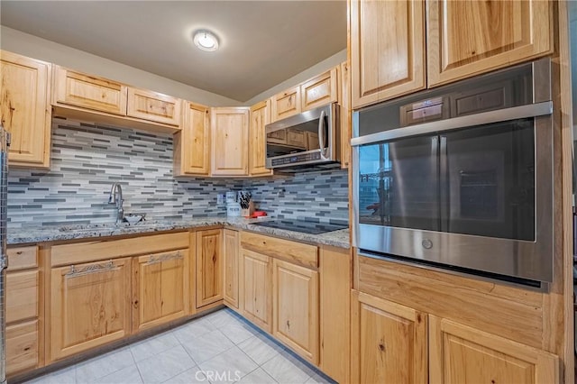 kitchen with appliances with stainless steel finishes, sink, decorative backsplash, light stone counters, and light brown cabinets